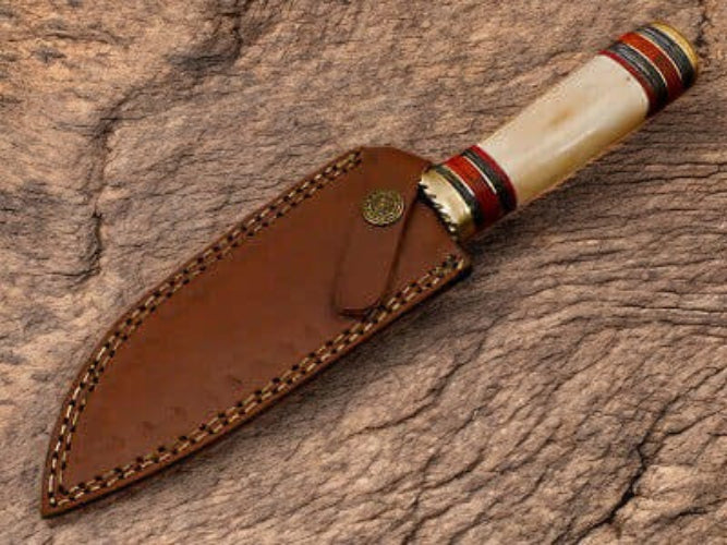 Decorative knife with a leather sheath on a wooden surface