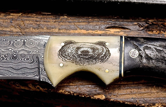 Close-up of a Damascus steel knife with an engraved handle on a wooden surface
