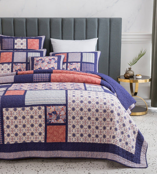 Patchwork quilt with floral patterns on a bed in a bedroom setting.