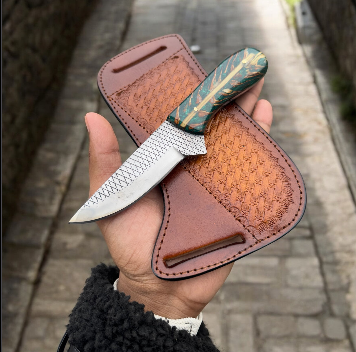 Decorative knife with leather sheath on a wooden surface
