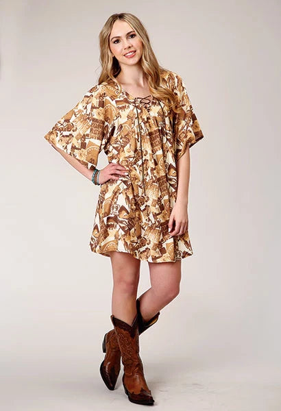 Woman wearing a patterned dress and brown boots on a plain background