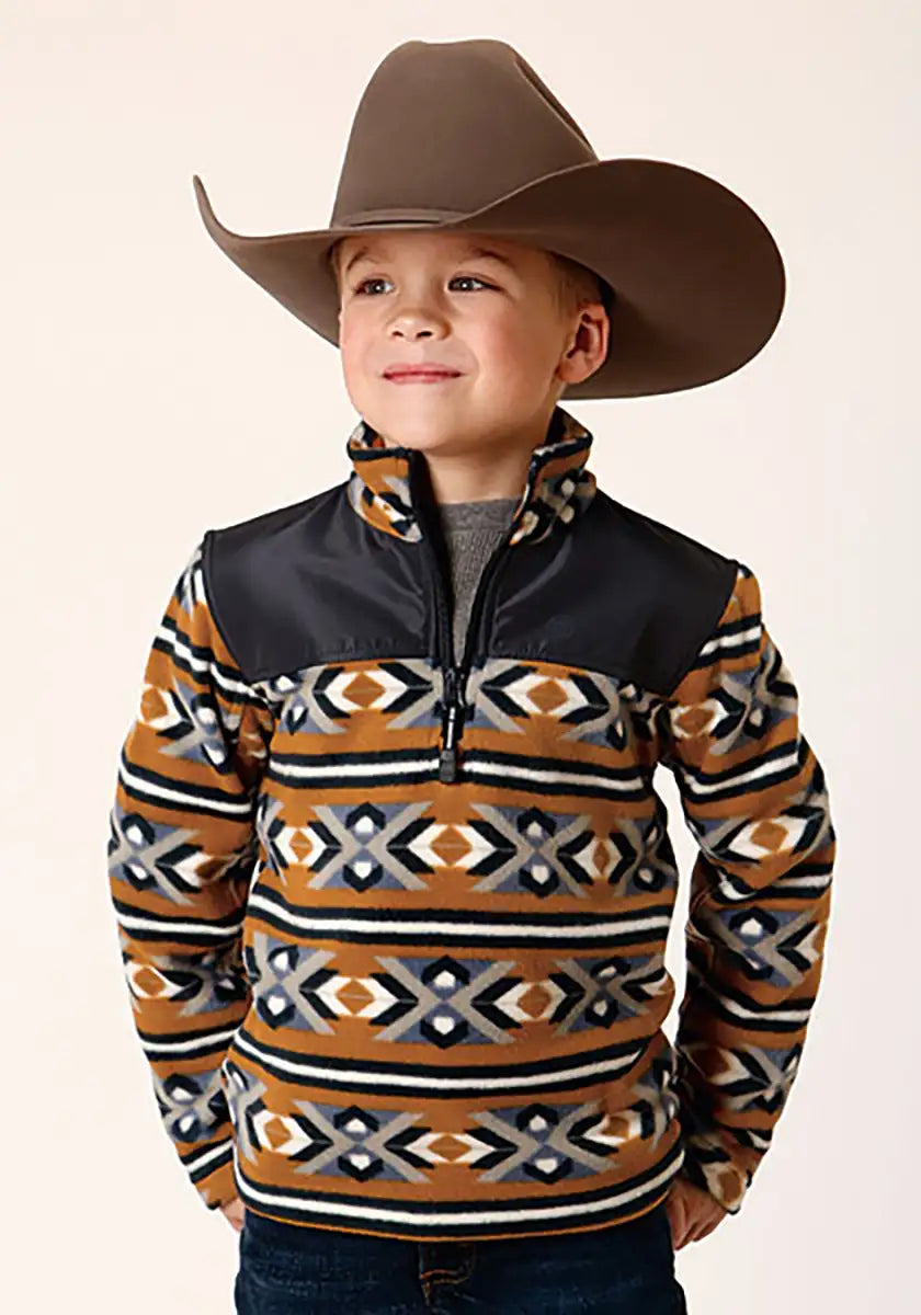 Child wearing a patterned pullover with a brown cowboy hat on a beige background