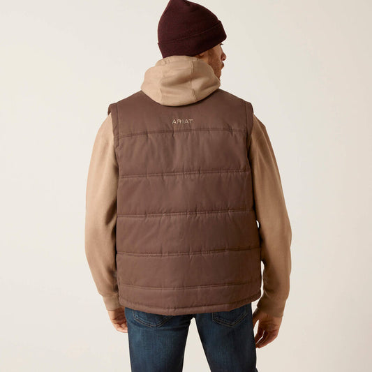 Person wearing a brown puffer vest with a hood on a plain background