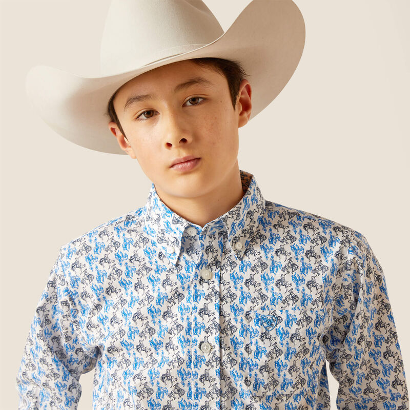 Young boy wearing a cowboy hat and patterned shirt against a plain background
