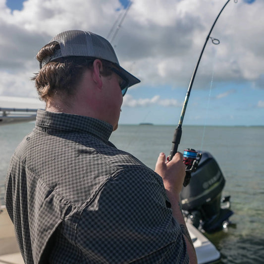 Person fishing on a boat with a cloudy sky and water background