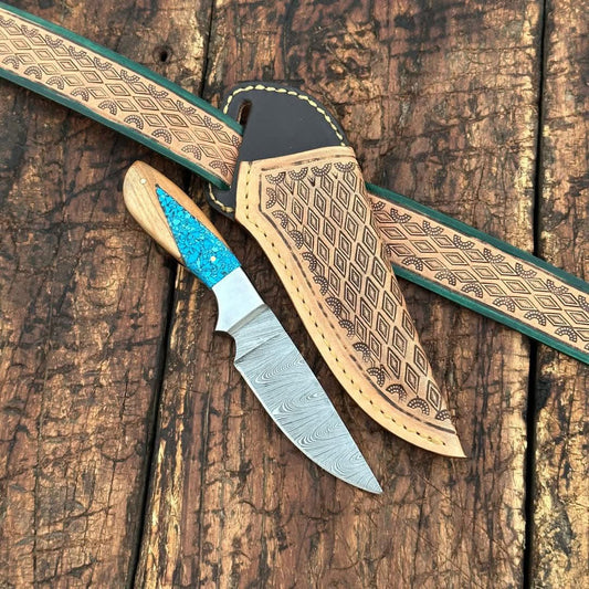 Decorative knife with turquoise handle and leather sheath on wooden surface