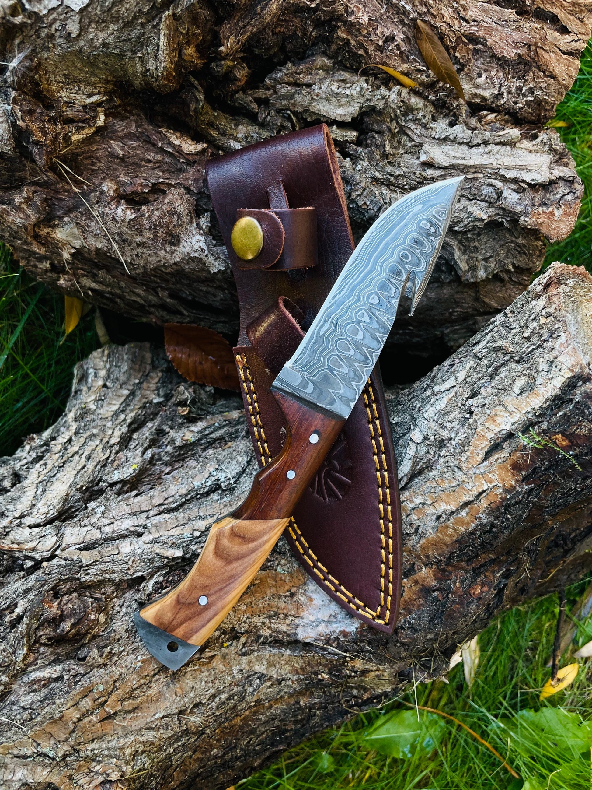 Knife with wooden handle and leather sheath on a wooden surface