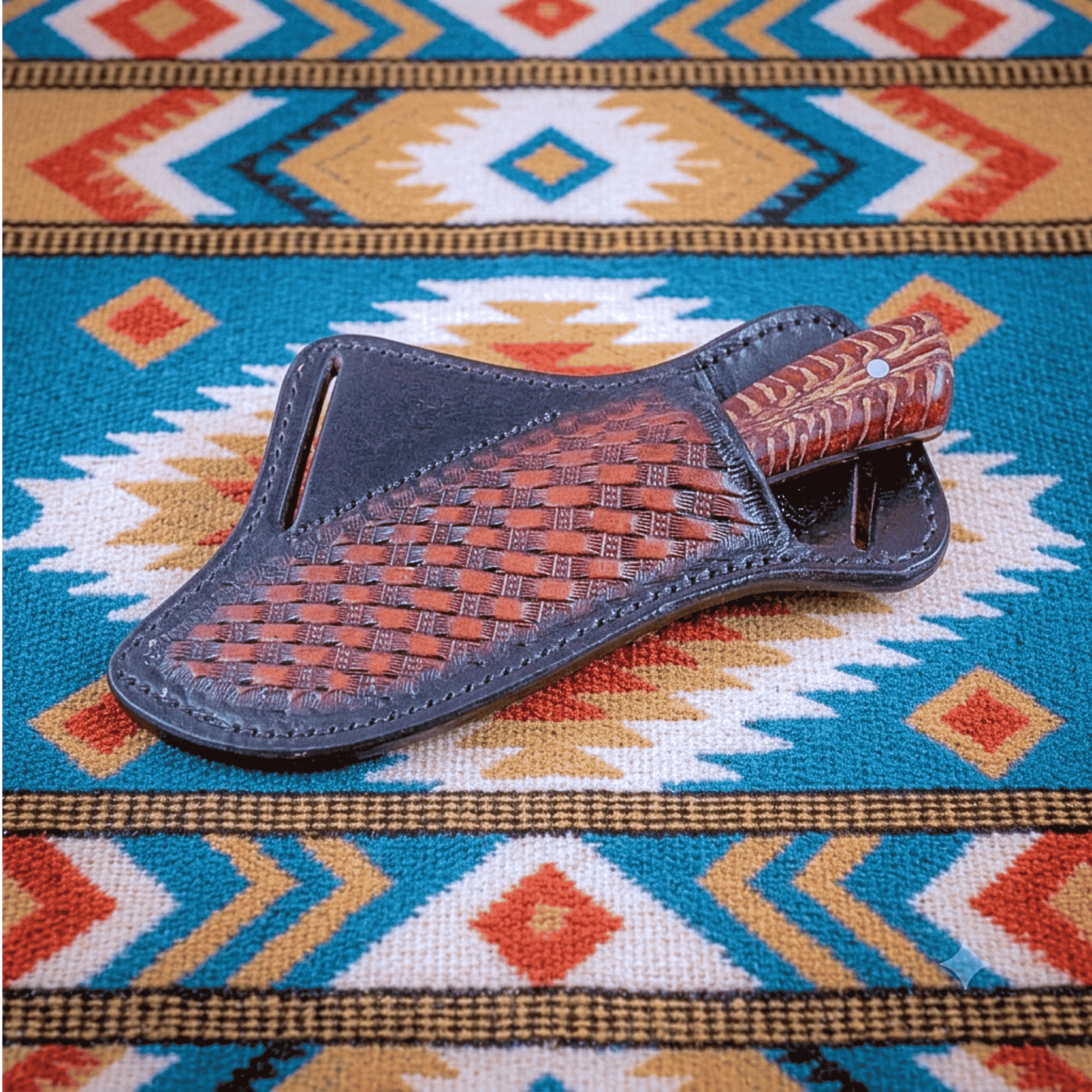 Red Mesa knife in leather sheath. Red pine cone handle showing out of sheath. Western style horse blanket in back ground. 
