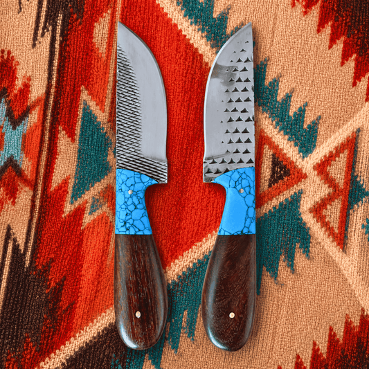 Two rasp steel cowboy knives with textured silver blades and bright blue mosaic handles, displayed on a colorful Southwestern-style woven rug.