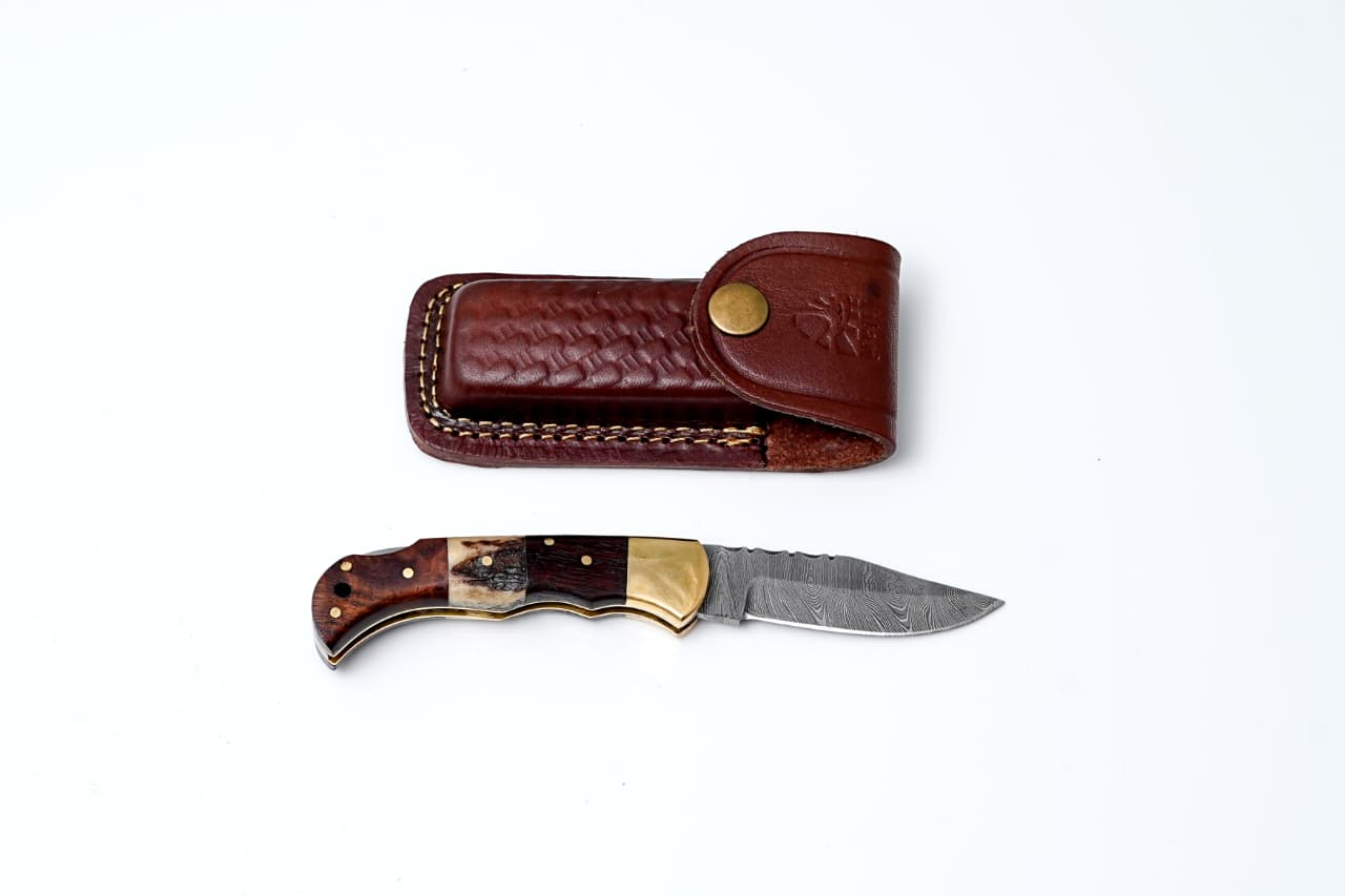 Folding knife with brown handle and leather sheath on a white background