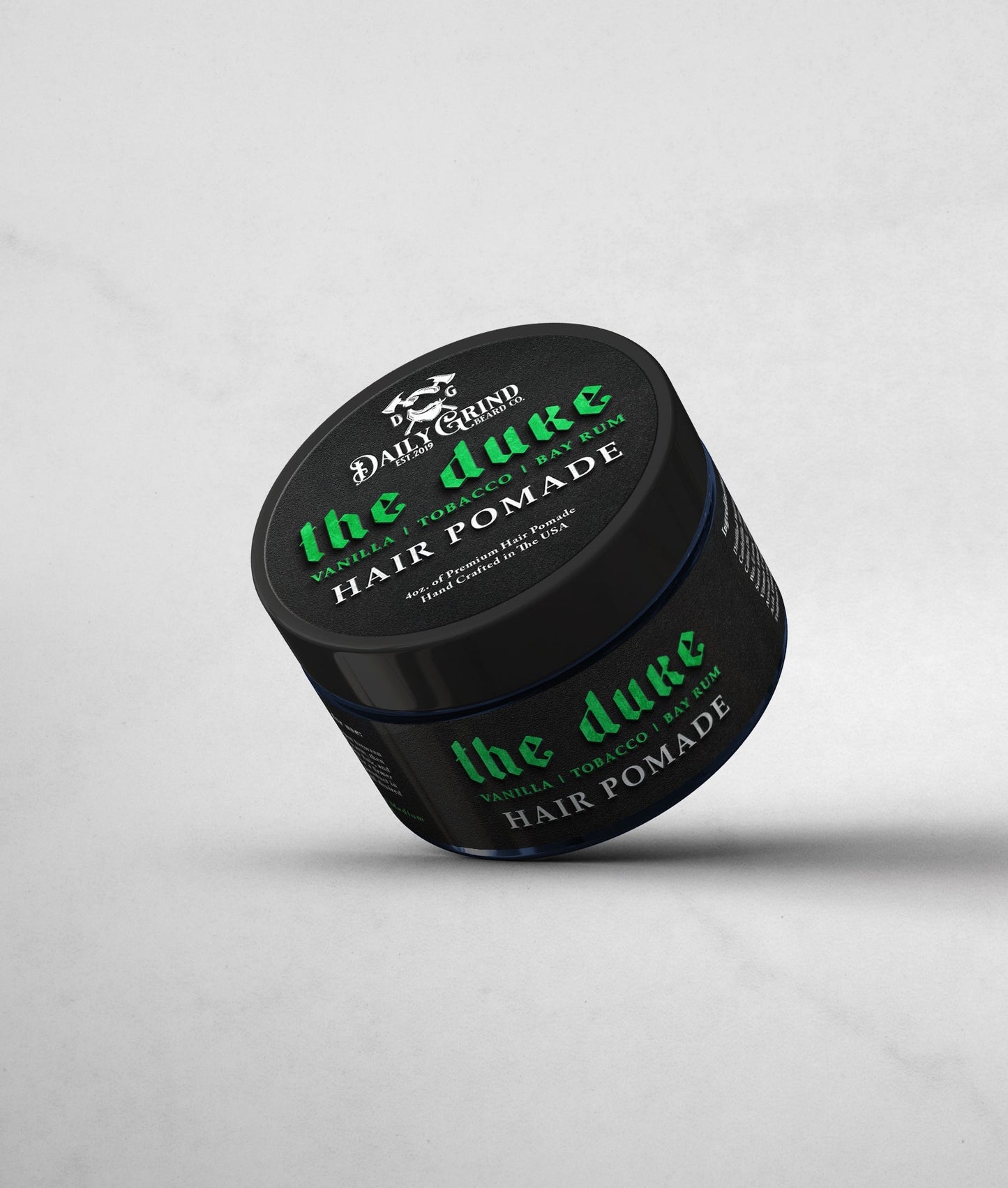 Jar of 'the duke' hair pomade with black lid and green text on a light gray background