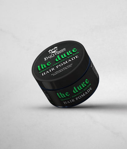Jar of 'the duke' hair pomade with black lid and green text on a light gray background