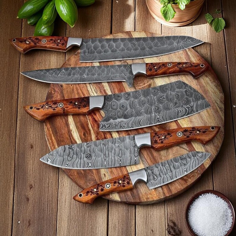 Set of five Damascus steel kitchen knives with wooden handles on a wooden cutting board.
