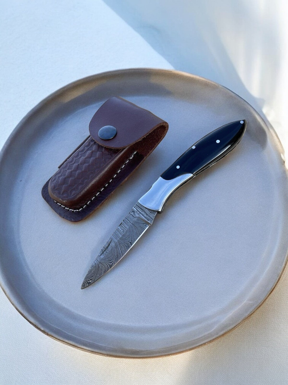 Knife with leather sheath on a ceramic plate