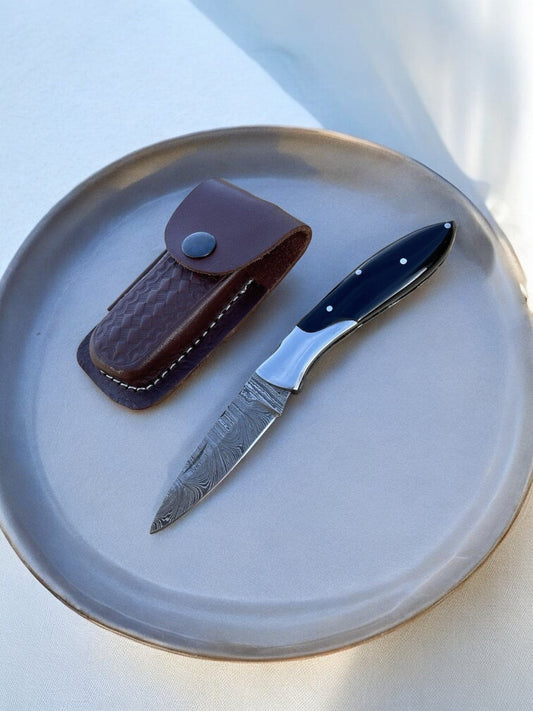 Knife with leather sheath on a ceramic plate