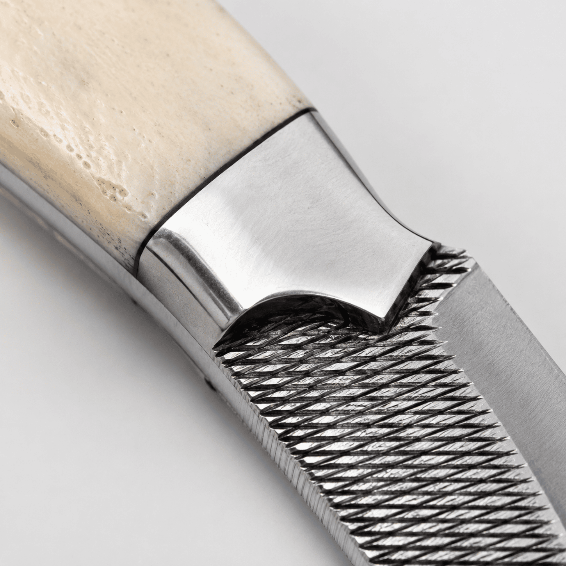 Close-up of the Silver Badlands bone handle, polished steel bolster, brass pins, full tang construction, and handcrafted rasp tool steel blade.