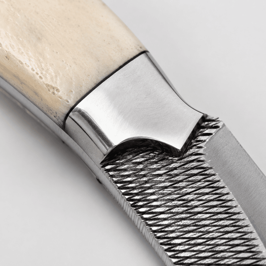 Close-up of the Silver Badlands bone handle, polished steel bolster, brass pins, full tang construction, and handcrafted rasp tool steel blade.