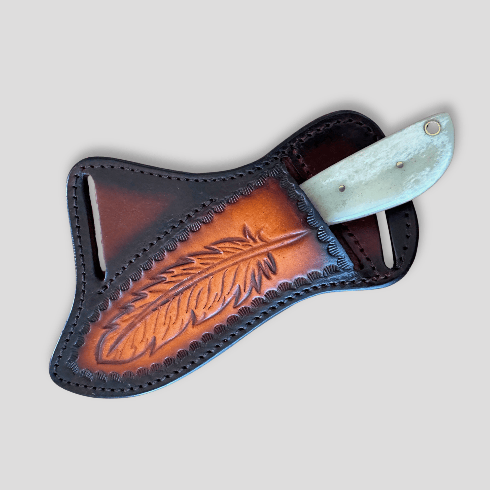 Feather-tooled leather cross draw pancake sheath with the Silver Badlands handmade bone ranch knife partially inserted.